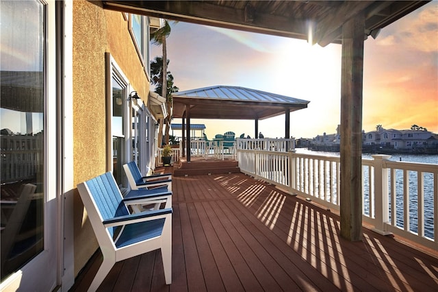 deck at dusk with a gazebo and a water view