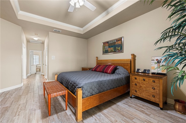 bedroom with ceiling fan, light hardwood / wood-style floors, crown molding, and a tray ceiling