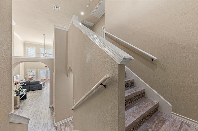 stairway with ornamental molding and hardwood / wood-style flooring