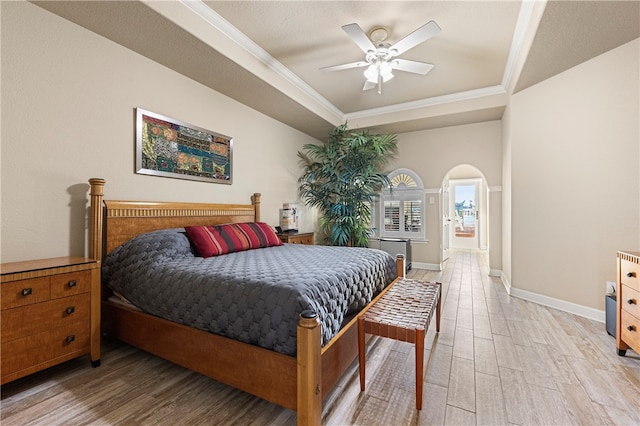 bedroom with light hardwood / wood-style floors, a raised ceiling, ceiling fan, and crown molding