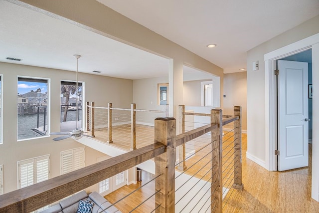 corridor with a water view and light hardwood / wood-style floors