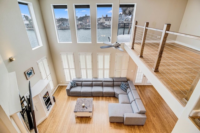 living room with a water view, a towering ceiling, and light hardwood / wood-style flooring