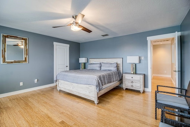 bedroom with ceiling fan, light hardwood / wood-style flooring, and a textured ceiling