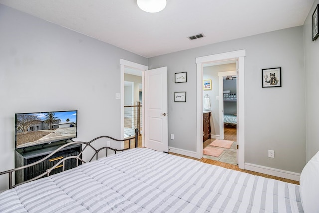 bedroom with light hardwood / wood-style flooring and ensuite bathroom