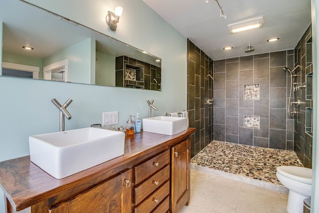 bathroom with vanity, tile patterned floors, toilet, and tiled shower