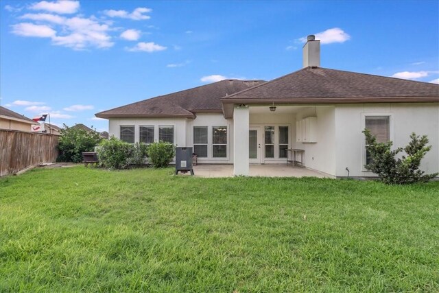 back of property featuring a chimney, a lawn, a patio area, fence, and stucco siding