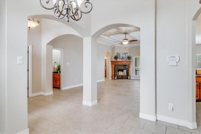 interior space with a fireplace, arched walkways, ceiling fan with notable chandelier, beamed ceiling, and coffered ceiling