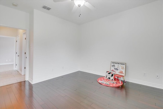 spare room featuring baseboards, ceiling fan, wood finished floors, and visible vents