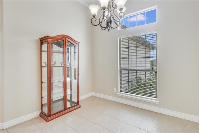 empty room with baseboards, tile patterned flooring, and a notable chandelier