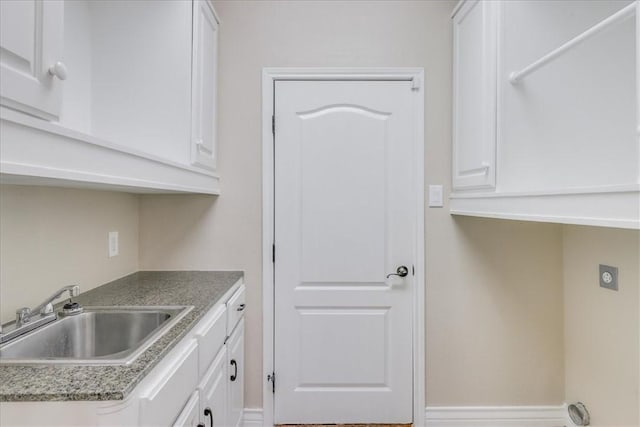 laundry room featuring electric dryer hookup, a sink, and cabinet space