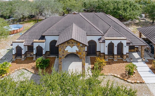 view of front facade featuring stone siding, a tile roof, and stucco siding