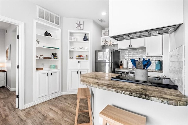 14721 Whitecap Blvd Unit 115, Corpus Christi, TX 78418 - kitchen with freestanding refrigerator, light wood finished floors, white cabinetry, stone countertops, and a breakfast bar area