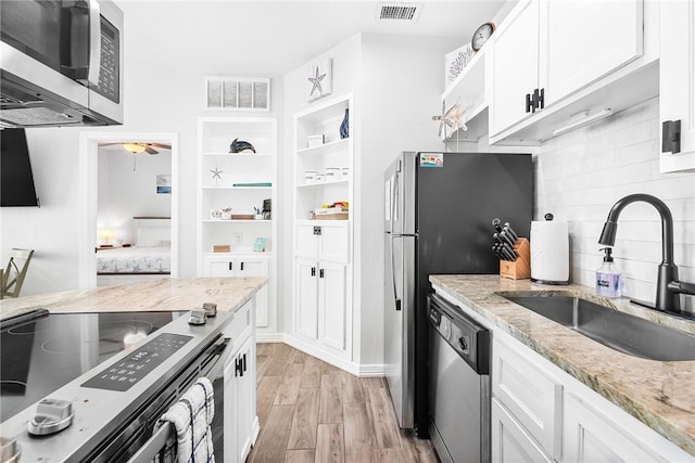 14721 Whitecap Blvd Unit 115, Corpus Christi, TX 78418 - kitchen with appliances with stainless steel finishes, white cabinetry, light wood-style floors, and backsplash