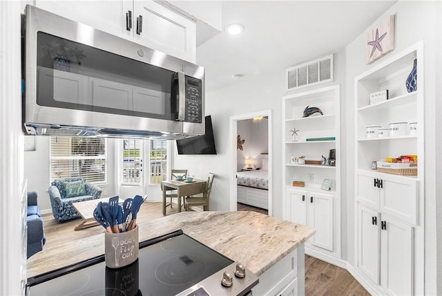 14721 Whitecap Blvd Unit 115, Corpus Christi, TX 78418 - kitchen featuring stainless steel microwave, wood finished floors, light stone counters, white cabinets, and open shelves