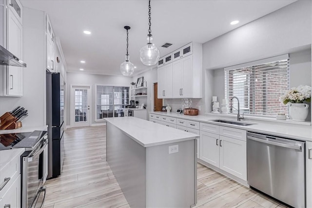 kitchen featuring white cabinetry, sink, hanging light fixtures, a kitchen island, and appliances with stainless steel finishes