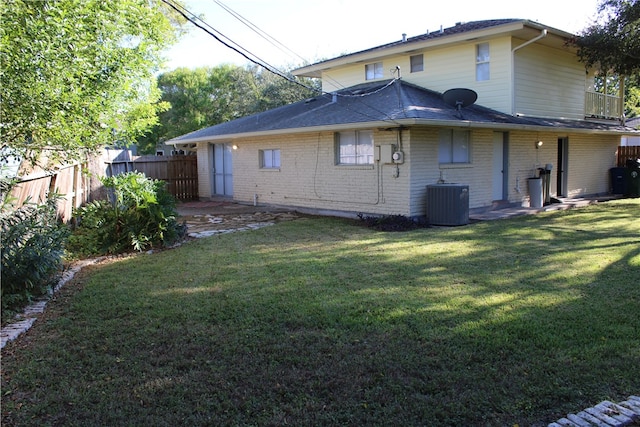 back of property with central air condition unit, a yard, and a balcony