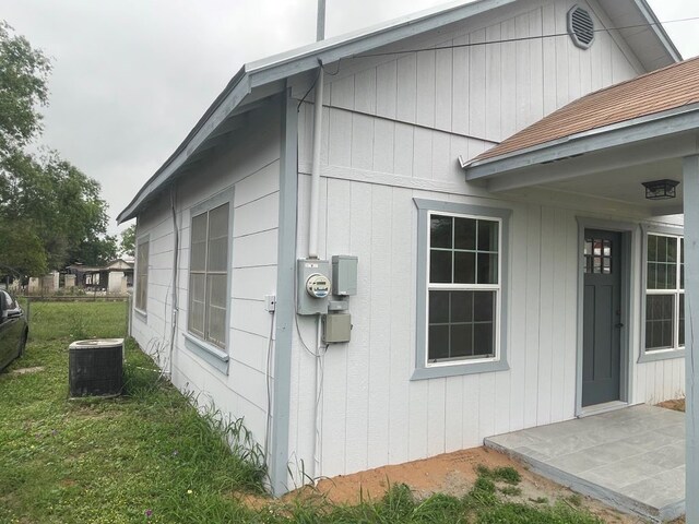 view of side of property featuring central AC and a yard