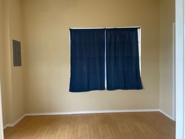 empty room featuring electric panel and light hardwood / wood-style floors