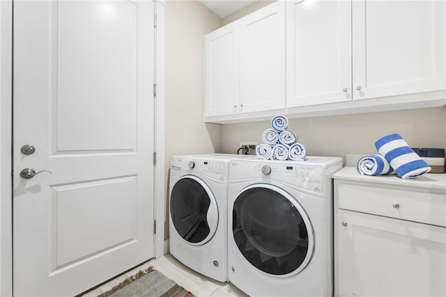 clothes washing area with separate washer and dryer and cabinet space