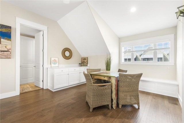 dining space featuring dark wood-style flooring, vaulted ceiling, and baseboards