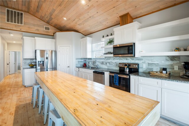 kitchen with white cabinets, decorative backsplash, light hardwood / wood-style flooring, wood counters, and appliances with stainless steel finishes