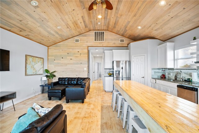 living room with wooden walls, sink, light hardwood / wood-style floors, wooden ceiling, and ceiling fan