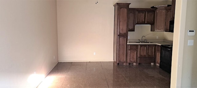 kitchen with black electric range, dark brown cabinets, and sink