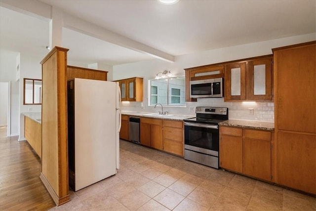 1009 Driftwood Pl, Corpus Christi, TX 78411 - kitchen featuring stainless steel appliances, decorative backsplash, beam ceiling, glass insert cabinets, and brown cabinets
