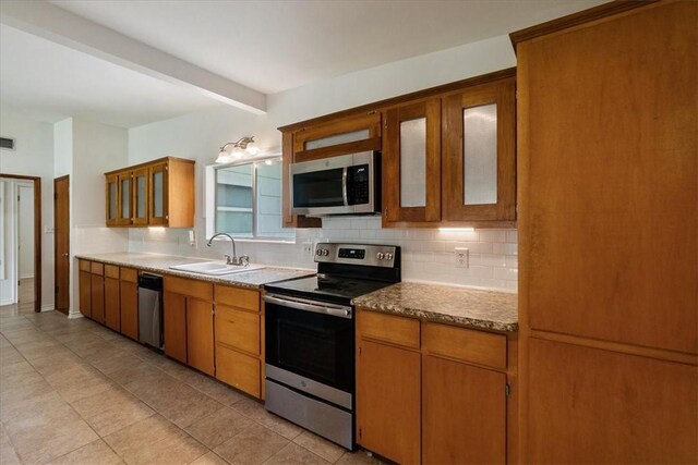 1009 Driftwood Pl, Corpus Christi, TX 78411 - kitchen with stainless steel appliances, tasteful backsplash, light tile patterned floors, glass insert cabinets, and beam ceiling