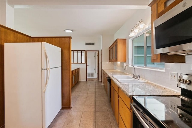 1009 Driftwood Pl, Corpus Christi, TX 78411 - kitchen with appliances with stainless steel finishes, brown cabinets, and backsplash