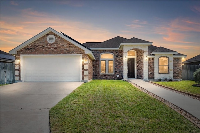 view of front of house with a yard, driveway, fence, and an attached garage
