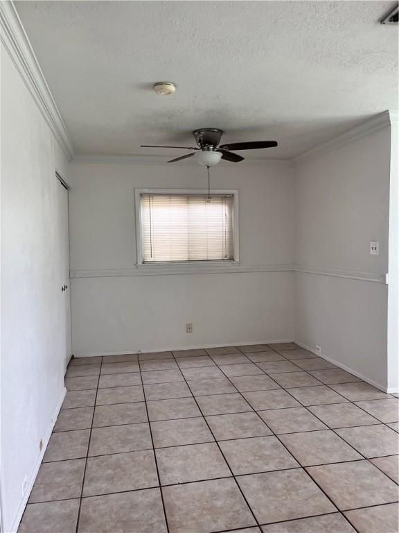 tiled empty room with a textured ceiling, ceiling fan, and crown molding