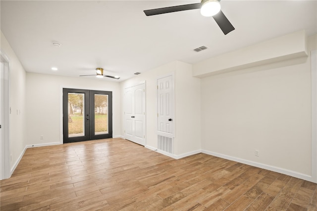 empty room with ceiling fan, light wood-type flooring, and french doors