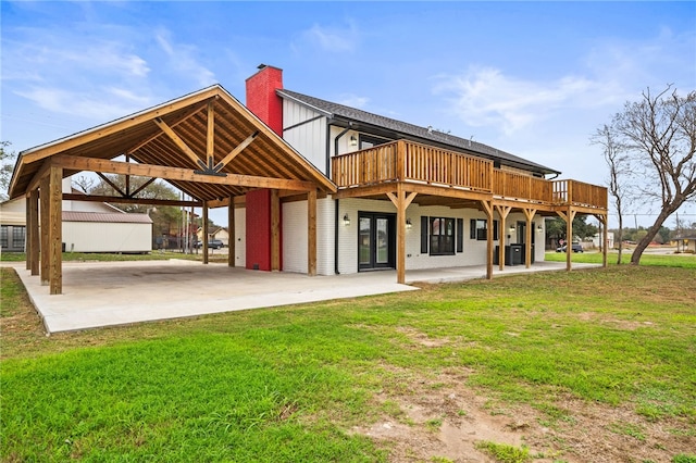 rear view of property with a deck, a patio area, and a lawn