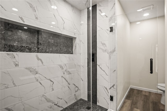 bathroom featuring wood-type flooring, a shower with shower door, and toilet