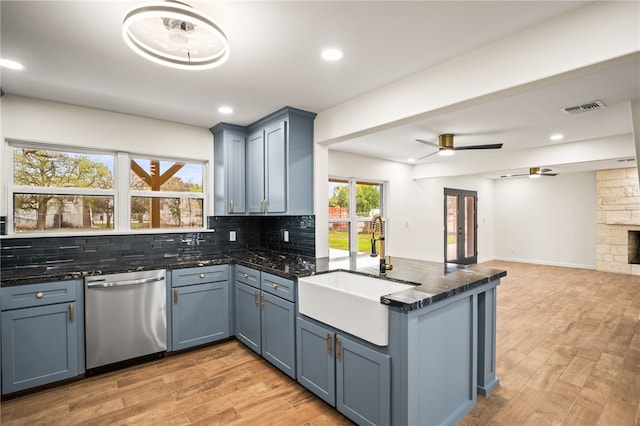 kitchen with tasteful backsplash, stainless steel dishwasher, kitchen peninsula, and sink