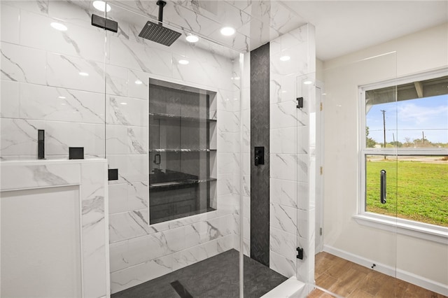 bathroom with hardwood / wood-style flooring, a shower with shower door, and a healthy amount of sunlight