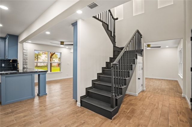 staircase featuring wood-type flooring, sink, and ceiling fan