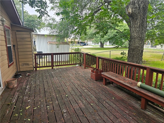 wooden deck with a storage unit and a lawn