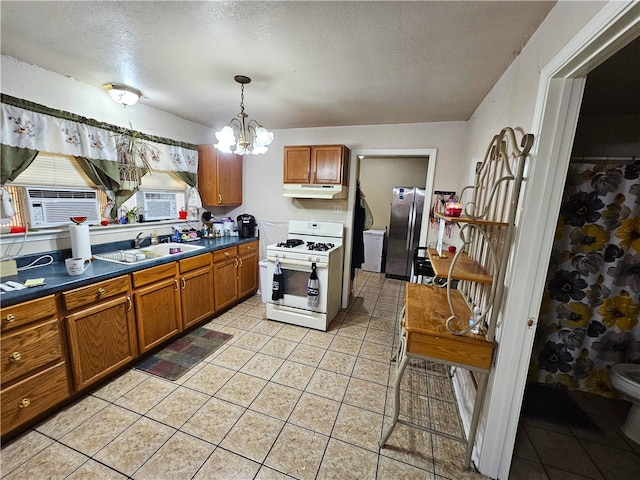 kitchen featuring sink, white range with gas stovetop, a notable chandelier, stainless steel fridge, and pendant lighting