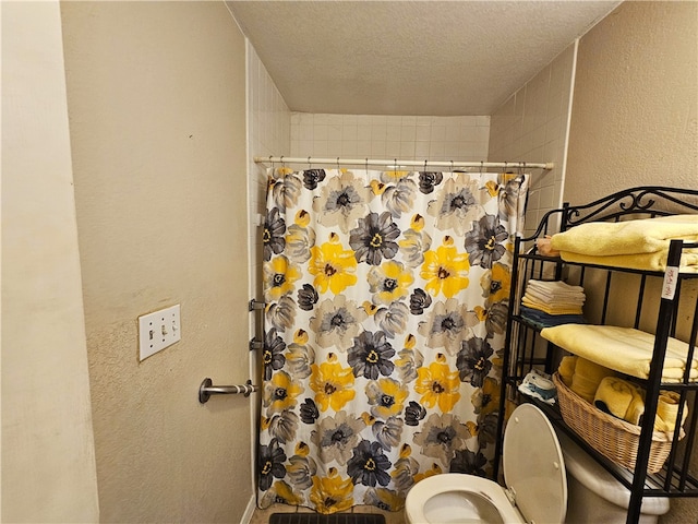 bathroom featuring toilet, a textured ceiling, and curtained shower