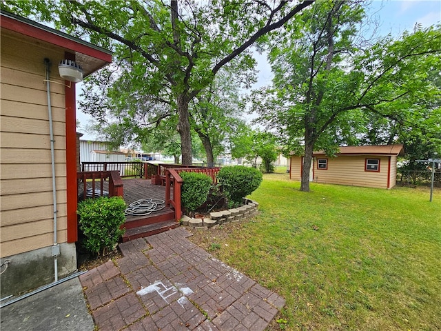 view of yard featuring an outdoor structure, a wooden deck, and a patio area