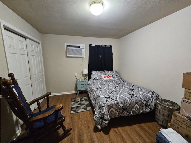 bedroom with dark wood-type flooring, a closet, a textured ceiling, and a wall mounted AC