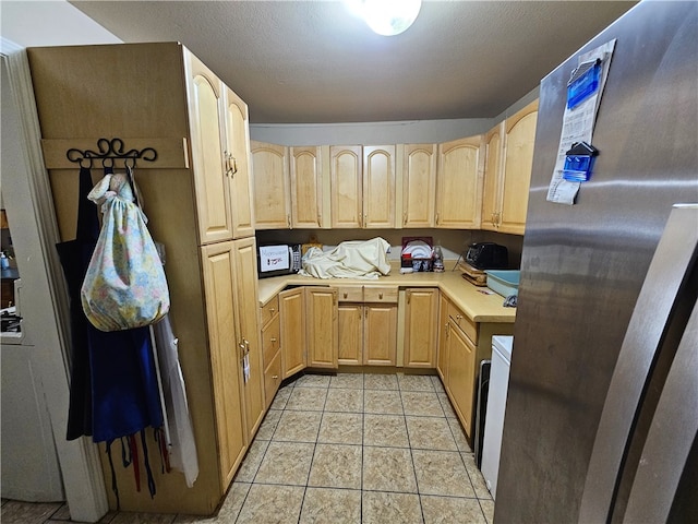 kitchen featuring light tile patterned floors, light brown cabinetry, and stainless steel fridge