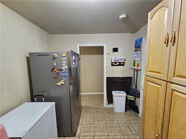 kitchen featuring light tile patterned flooring, light brown cabinetry, stainless steel refrigerator, and refrigerator