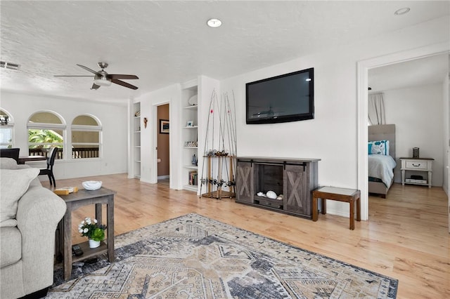 109 Tarpon Ct, Aransas Pass, TX 78336 - living room featuring built in shelves, ceiling fan, wood finished floors, and a textured ceiling
