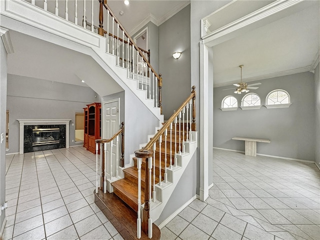 4513 Ammer Lake Dr, Corpus Christi, TX 78413 - staircase with a ceiling fan, crown molding, a premium fireplace, tile patterned floors, and a towering ceiling