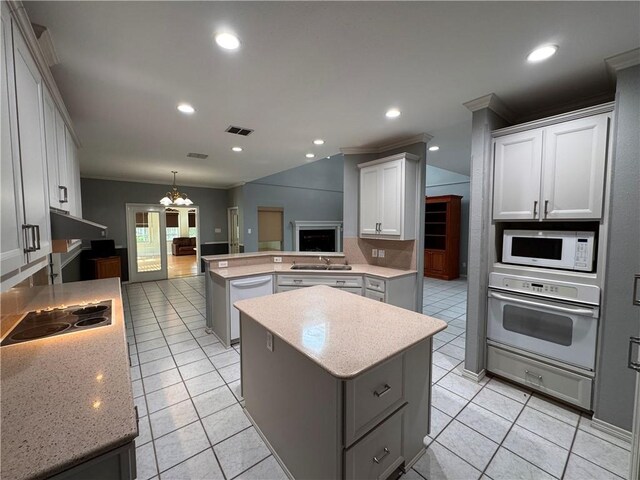 4513 Ammer Lake Dr, Corpus Christi, TX 78413 - kitchen with a peninsula, white appliances, a chandelier, a kitchen island, and light tile patterned flooring