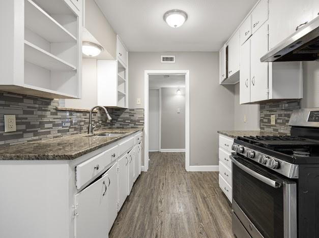 6022 Norvel Dr, Corpus Christi, TX 78412 - kitchen featuring stainless steel range with gas stovetop, open shelves, exhaust hood, and white cabinetry