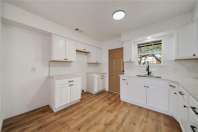 2442 Bevecrest Dr, Corpus Christi, TX 78415 - kitchen with white cabinets, a sink, light wood finished floors, and visible vents